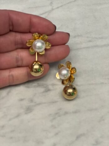 Aretes dorados en forma de flor con pétalos brillantes y perla central